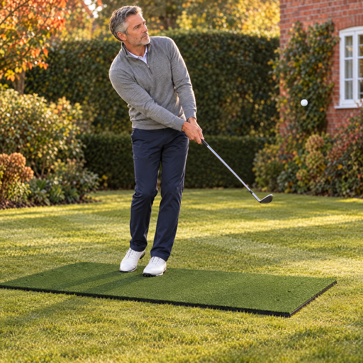 Golfer chipping off the hitting mat in a British back garden