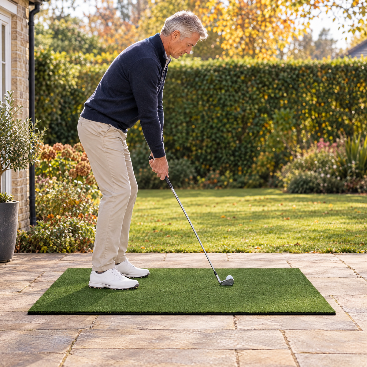 Golfer at address on the hitting mat on a garden patio